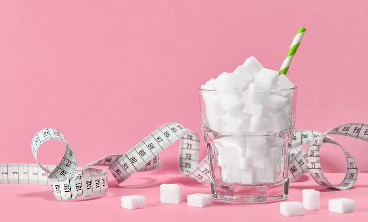 Glass with sugar cubes and measuring tape.